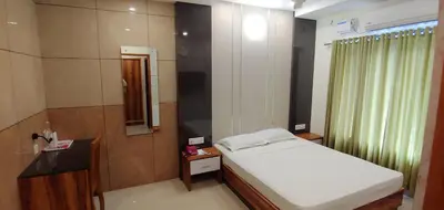 a bedroom with a white bed and a mirror at Sree Gokulam Sabari in Guruvāyūr