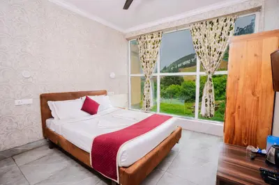 a bedroom with a bed and a large window at Tulips Valley View Resorts in Ooty