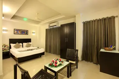 a hotel room with a bed and a table and chairs at Park Residency Koyilandi in Quilāndi