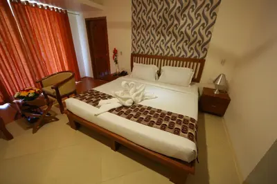 a bedroom with a bed and a chair in a room at Park regency in Angamali