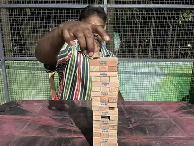 a man is playing with a wooden block at Greenwoods Nature Camp in Mudumalai National Park