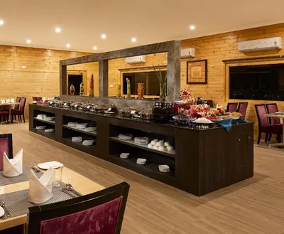 a restaurant with a counter with food on it at Sterling Anaikatti in Varagampadi