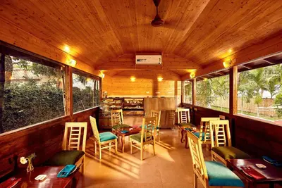 a restaurant with tables and chairs and windows at Sterling Anaikatti in Varagampadi