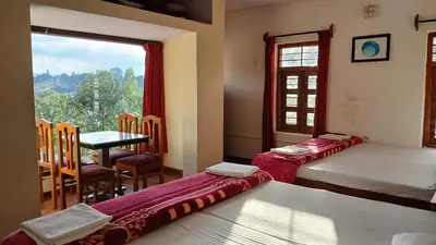 a room with two beds and a table and a window at Satya Anand Cottage Pure Veg and Non Alcoholic Hotel in Coonoor