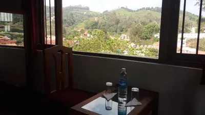 a bottle of water sitting on a table in front of a window at Satya Anand Cottage Pure Veg and Non Alcoholic Hotel in Coonoor