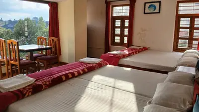 a room with three beds and a table and a window at Satya Anand Cottage Pure Veg and Non Alcoholic Hotel in Coonoor