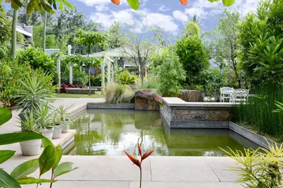a garden with a pond in the middle at Purple Palms Resort & Spa in Kushālnagar