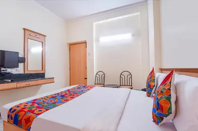 a bedroom with a bed and a tv and a mirror at FabHotel ESS Paradise in Coimbatore