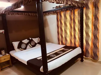 a bedroom with a four poster bed with black posts at Palm Era Resorts in Kushālnagar