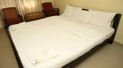 a bed with white sheets and pillows in a room at Palm Era Resorts in Kushālnagar