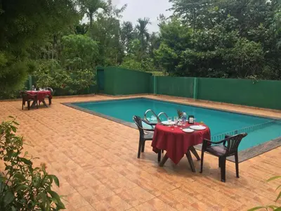 a patio with a table and chairs next to a pool at Palm Era Resorts in Kushālnagar