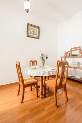 a dining room table with three chairs and a vase of flowers at Fairy Glen in Coonoor
