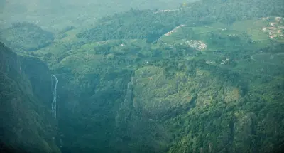 an aerial view of a mountain valley with a waterfall at Fairy Glen in Coonoor