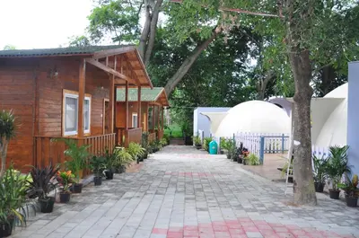 a walkway leading to a house and a tent at KSTDC Hotel Mayura Riverview Srirangapatna in Seringapatam