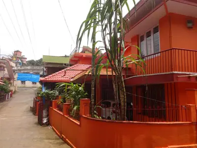 a red house with a palm tree in front of it at Four Seasons Home Stay (1BDH) in Madikeri
