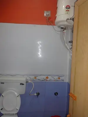 a bathroom with a toilet and a water tank at Four Seasons Home Stay (1BDH) in Madikeri