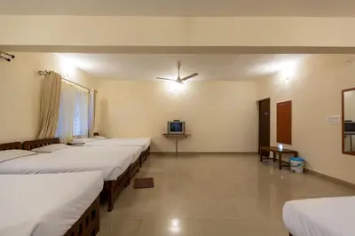 a room with a row of beds and a tv at KSTDC Hotel Mayura Hoysala, Mysore in Mysore