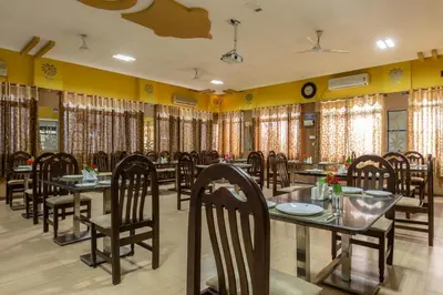 a dining room with tables and chairs and curtains at KSTDC Hotel Mayura Hoysala, Mysore in Mysore