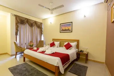 a bedroom with a large bed with a red blanket at KSTDC Hotel Mayura Hoysala, Mysore in Mysore