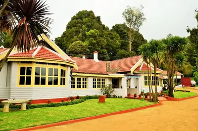 a white house with a red roof and palm trees at KSTDC Hotel Mayura Sudarshan ,Ooty in Ooty