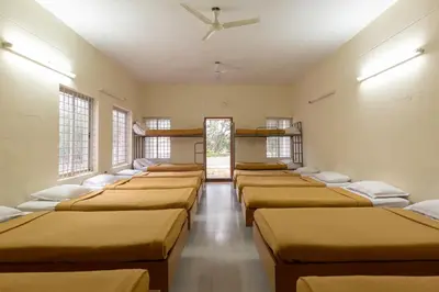 a row of beds in a room with windows at KSTDC Hotel Mayura Sangama Mekedatu in Mulhalli