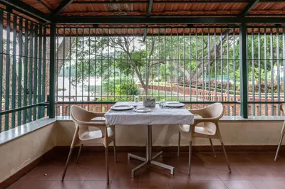 a table and chairs in a room with a large window at KSTDC Hotel Mayura Sangama Mekedatu in Mulhalli