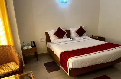 a bedroom with a bed with pillows and a chair at KSTDC Hotel Mayura Sangama Mekedatu in Mulhalli