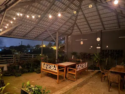 a patio with a table and chairs under a roof at Coorg North Breeze Homestay in Madikeri