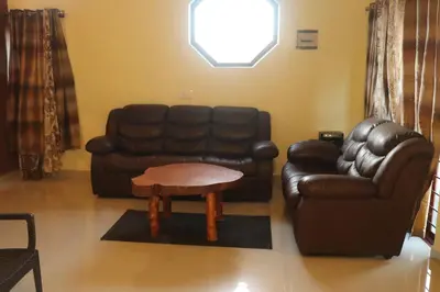 a living room with a leather couch and a coffee table at Coorg North Breeze Homestay in Madikeri