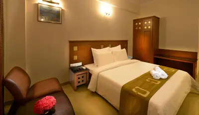 a hotel room with a bed and a chair at Plaza Inn in Coimbatore