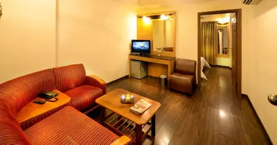 a hotel room with a couch and a table and a television at Plaza Inn in Coimbatore