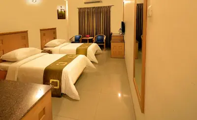 a hotel room with two beds and a kitchen at Plaza Inn in Coimbatore