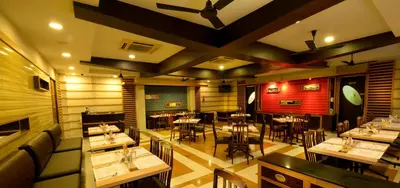 a restaurant with tables and chairs in a room at Plaza Inn in Coimbatore