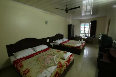 a hotel room with two beds and a television at Jays Inn in Munnar