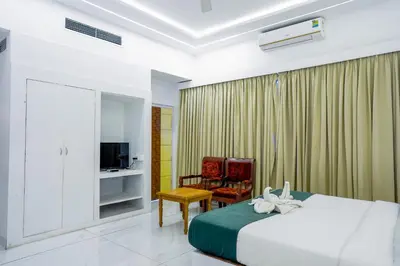 a bedroom with a bed and a chair and a television at Casino Hotels Ltd in Trichūr