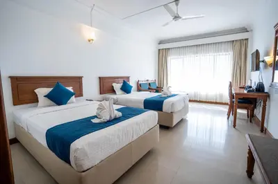 a hotel room with two beds and a desk at Casino Hotels Ltd in Trichūr