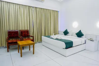 a bedroom with a bed and a chair and a table at Casino Hotels Ltd in Trichūr