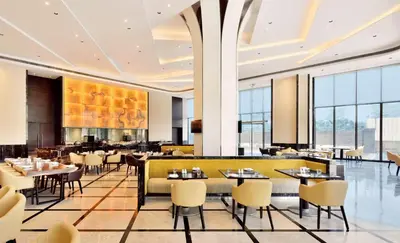 a restaurant with tables and chairs and windows at Radisson Blu Coimbatore in Coimbatore