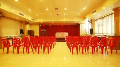 a conference room with red chairs and a stage with a table at Hotel Palace Tower in Trichūr