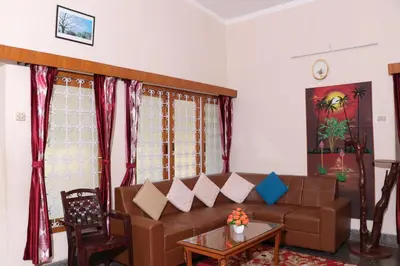 a living room with a brown couch and a table at Park corner Home stay in Coonoor