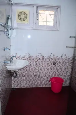 a bathroom with a sink and a red bucket at Park corner Home stay in Coonoor