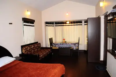 a bedroom with a bed and a dining room table at Park corner Home stay in Coonoor