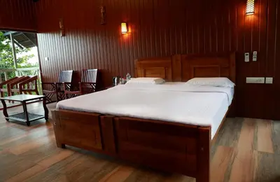 a bedroom with a large bed with white sheets at Woodrose Resort in Kalpetta