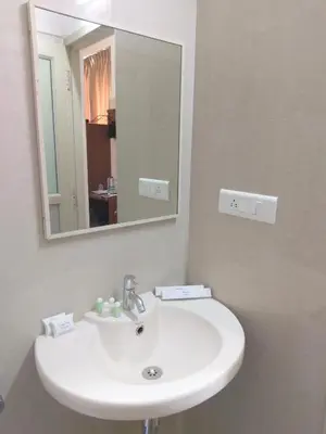 a bathroom with a white sink and a mirror at Banyan Tree Comforts Mysore in Mysore
