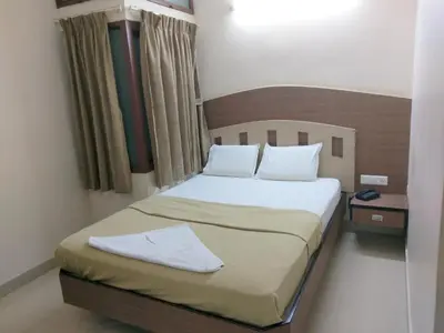 a bedroom with a bed with white sheets and pillows at Banyan Tree Comforts Mysore in Mysore