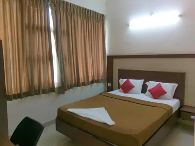a bedroom with a large bed with red pillows at Banyan Tree Comforts Mysore in Mysore