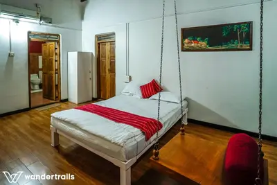 a swing bed in a room with a red blanket at Teak Town in Nilambūr