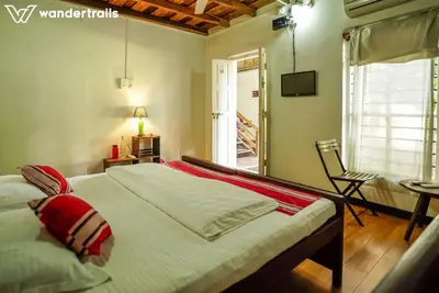 a bedroom with a bed and a chair and a window at Teak Town in Nilambūr
