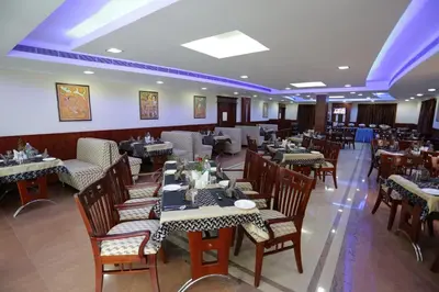 a restaurant with tables and chairs in a room at Hotel White City in North Paravur