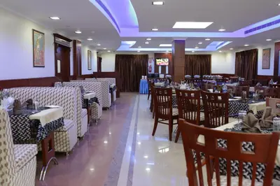 a dining room with tables and chairs in a restaurant at Hotel White City in North Paravur